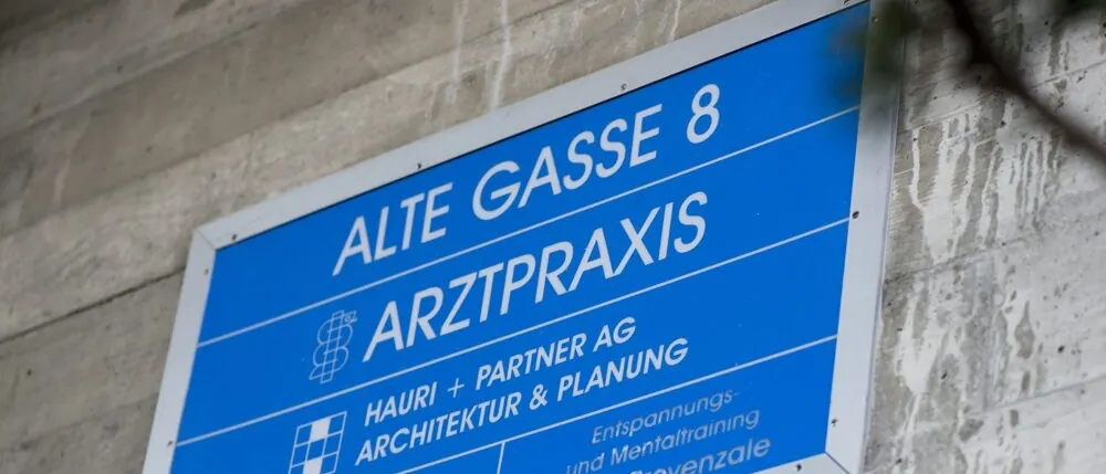 Hinweisschild «Alte Gasse 8 – Arztpraxis» am Gebäude in Suhr
