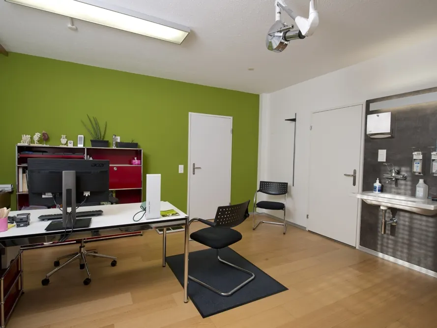 Sprechzimmer der Ärztegemeinschaft Suhr mit Schreibtisch und Untersuchungsliege