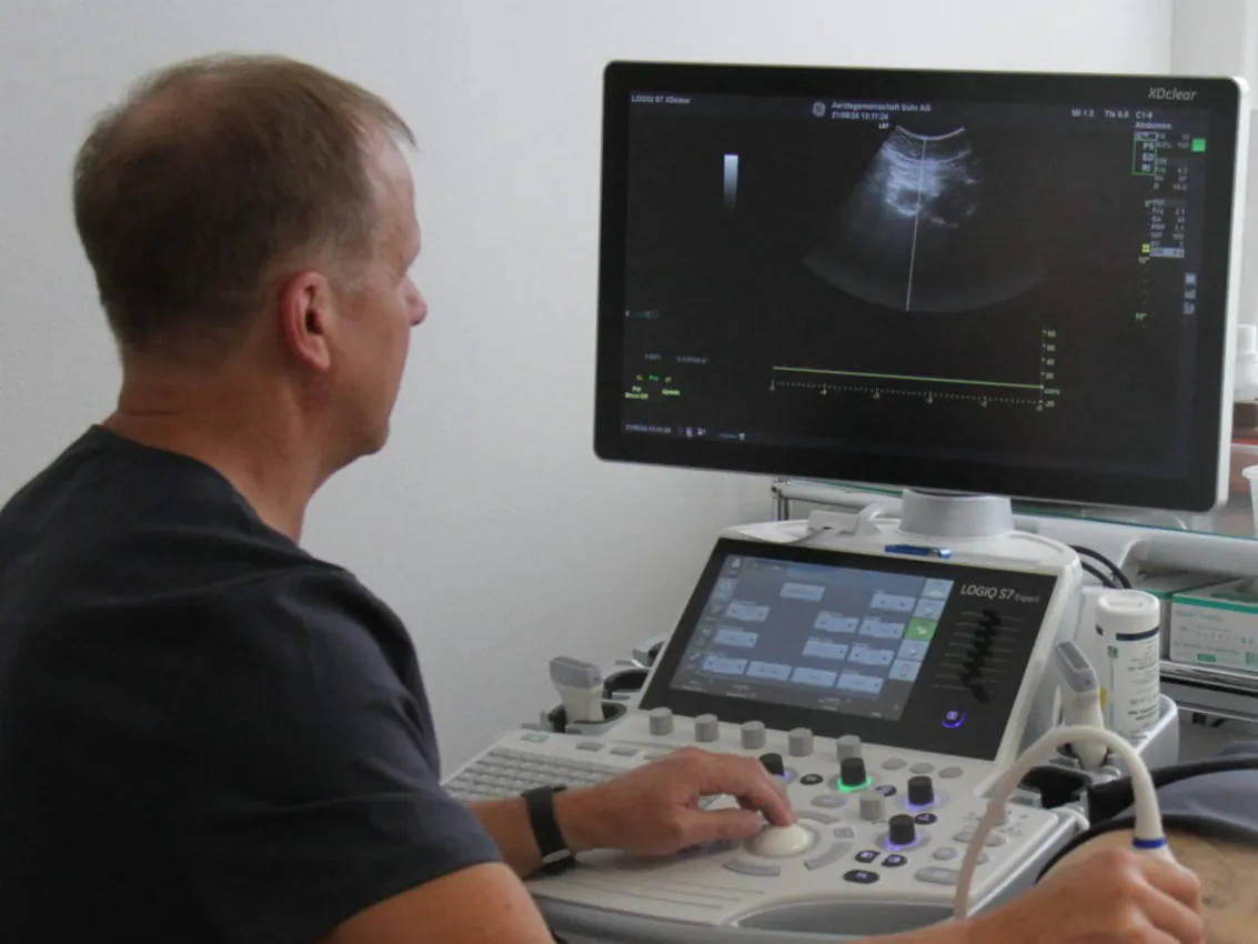 Hausarzt bei einer Ultraschalluntersuchung am Gerät in der Praxis Suhr